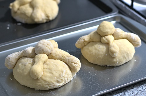 Panes de muerto sin hornear Pan de muerto armado sobre una bandeja antes de entrar al horno