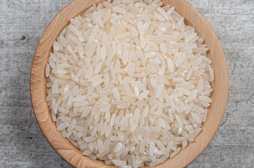 Arroz crudo Añadiendo el arroz al caldero para impregnarlo con el sofrito, paso clave en la receta de arroz con gandules.