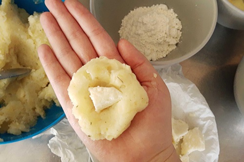 Armado bomas de papa Proceso manual de rellenar el puré de papa con cubos de queso y jamón cocido.