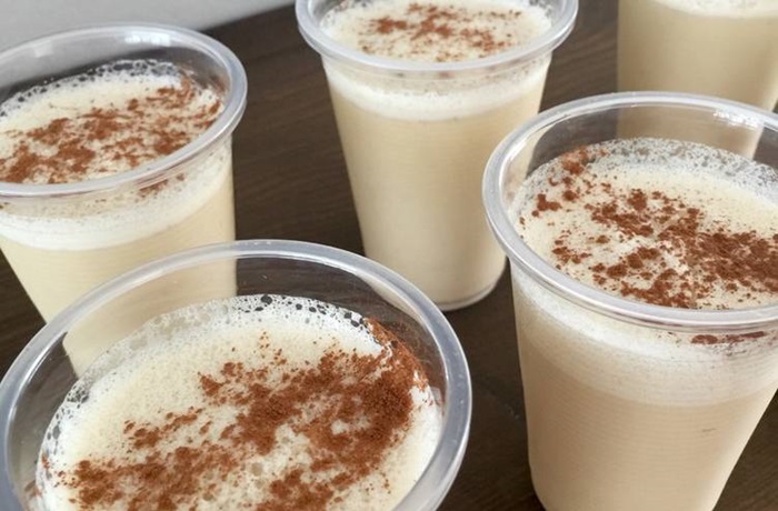 Limber de coco puertorriqueño: Receta tradicional boricua refrescante Varios vasos de plástico con limber de coco blanco y cremoso, con un toque de canela espolvoreada por encima.