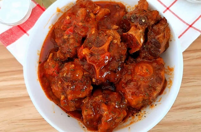 Un plato humeante de rabo encendido cubano con salsa roja espesa, decorado con perejil fresco.