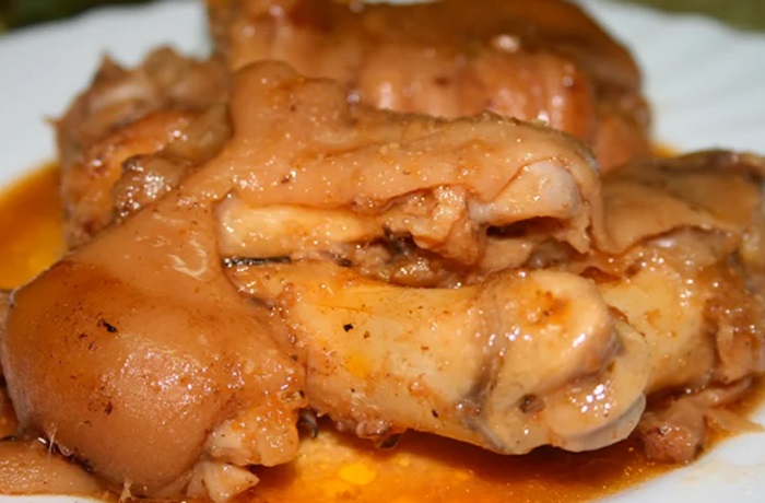 ¿Cómo hacer manitas de cerdo en salsa en olla express? Receta de la abuela Plato tradicional de manitas de cerdo en salsa española espesa decorado con una hoja de laurel y servido en una cazuela de barro.