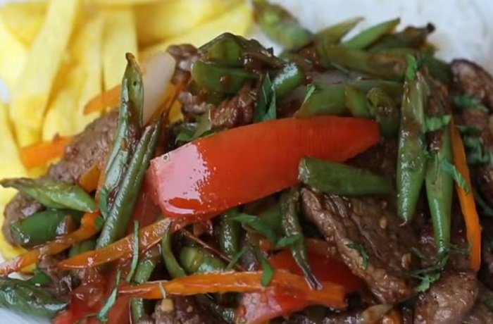 Vainita saltada con cebolla y tomate en sartén receta peruana