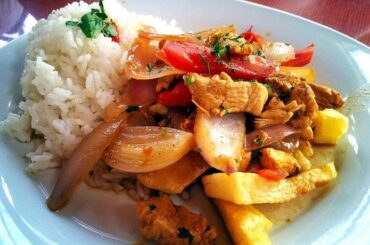 Lomo saltado de pollo con cebolla y tomate en sartén receta peruana