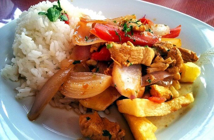 Lomo saltado de pollo con cebolla y tomate en sartén receta peruana