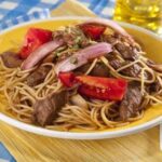 Tallarín saltado de carne con cebolla, tomate y ají amarillo receta peruana